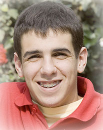 young man with braces smiling and sitting in front of blooming rose bushes