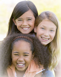 three young girls outside and smiling