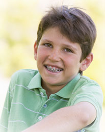 young boy with braces smiling and sitting outside